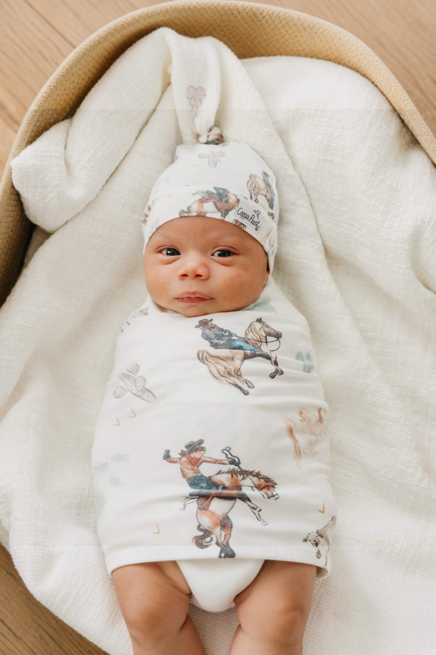 Copper Pearl Boone swaddle blanket wrapped around a baby.