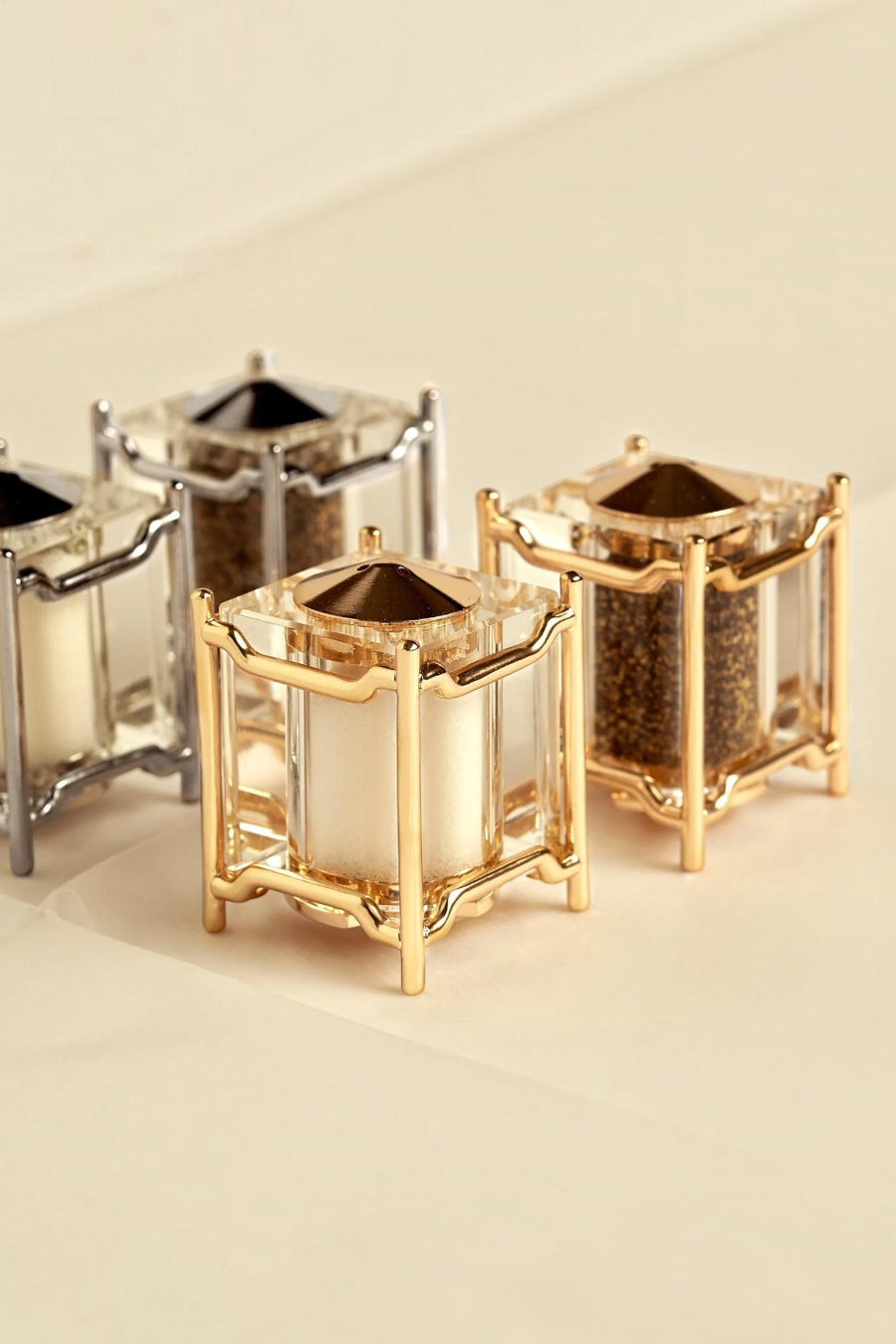 L'Objet Han Spice Jewels salt and pepper shakers in gold, filled and styled on a cream surface